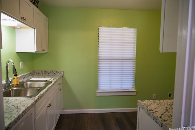 kitchen with light stone countertops, sink, dark hardwood / wood-style floors, white dishwasher, and white cabinets