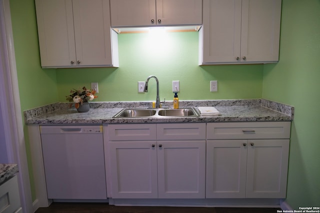 kitchen featuring white dishwasher, light stone counters, white cabinets, and sink