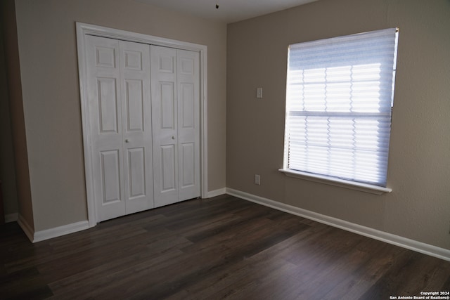 unfurnished bedroom featuring dark hardwood / wood-style flooring and a closet