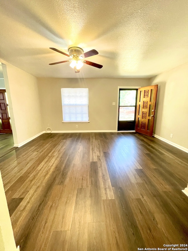 empty room featuring ceiling fan, dark wood-type flooring, and a textured ceiling