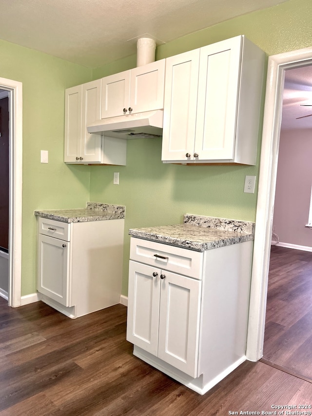 kitchen featuring dark hardwood / wood-style floors, light stone countertops, and white cabinetry