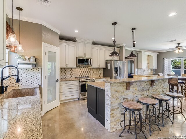 kitchen with pendant lighting, stainless steel appliances, sink, and light stone counters