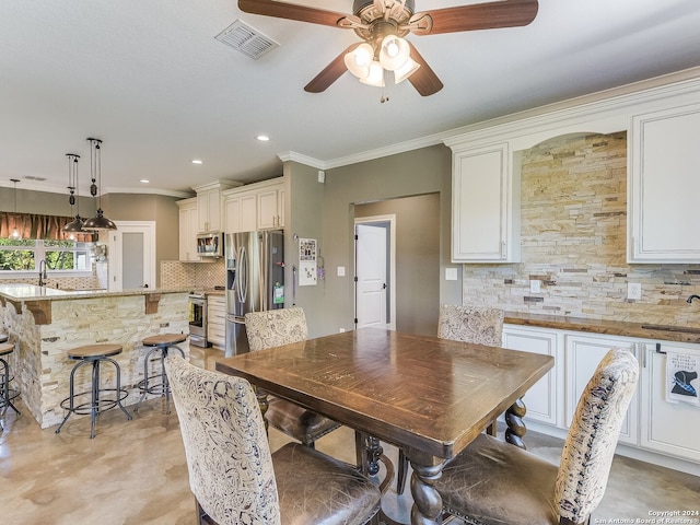 dining space featuring ceiling fan, sink, and ornamental molding