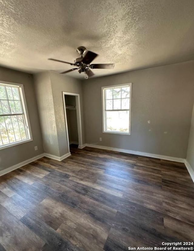 unfurnished bedroom with dark wood-type flooring, multiple windows, and a textured ceiling