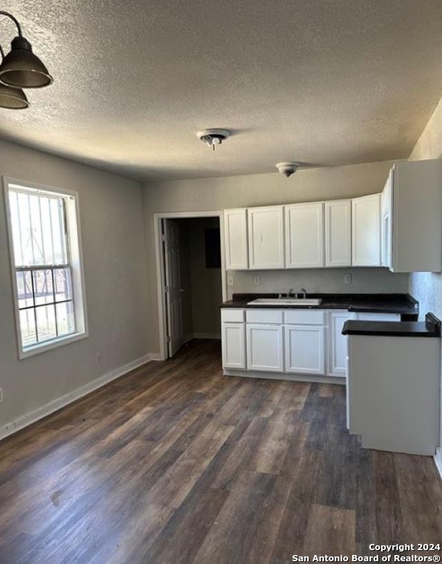 kitchen featuring dark wood-type flooring, white cabinetry, sink, and a textured ceiling