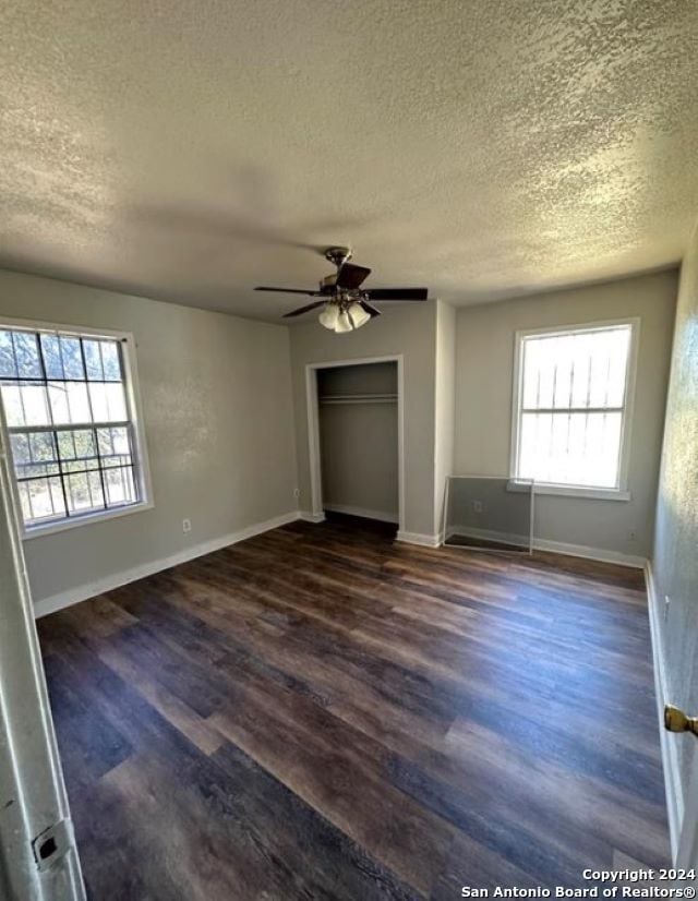 unfurnished bedroom featuring dark wood-type flooring, ceiling fan, and a textured ceiling