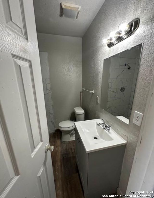 bathroom featuring toilet, vanity, a textured ceiling, and hardwood / wood-style flooring