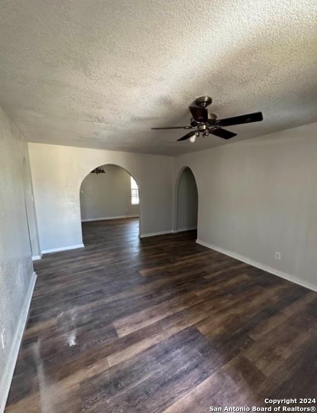 unfurnished room featuring dark wood-type flooring, a textured ceiling, and ceiling fan