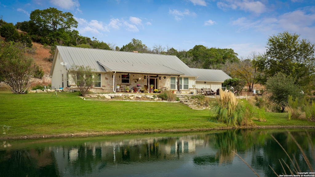 back of house with a yard and a water view