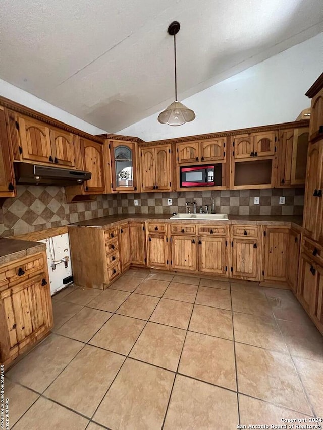 kitchen with backsplash, sink, pendant lighting, and lofted ceiling