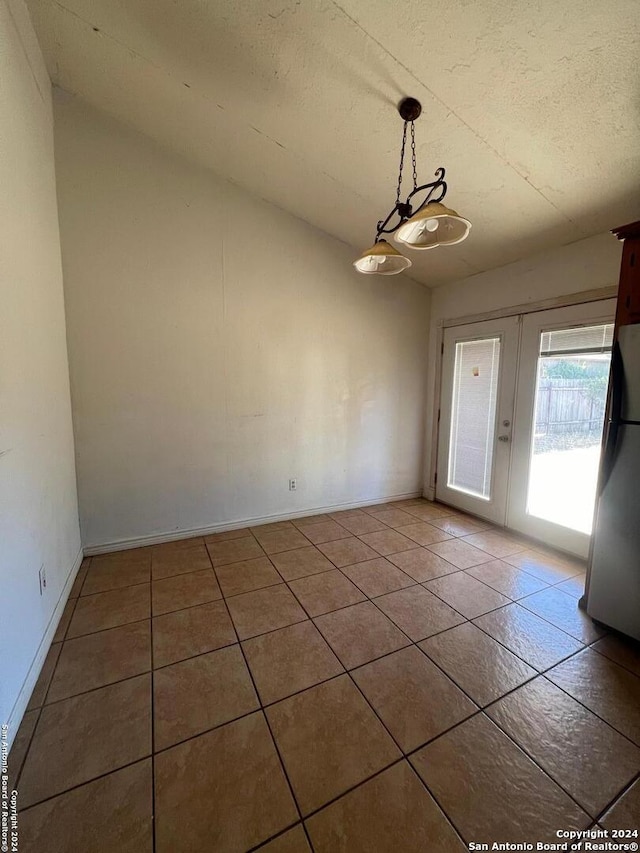 interior space featuring lofted ceiling, tile patterned floors, a textured ceiling, and french doors