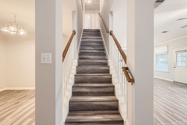 stairs featuring hardwood / wood-style flooring and an inviting chandelier