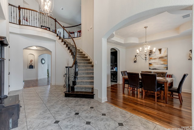 entrance foyer with a high ceiling, wood-type flooring, crown molding, and a tray ceiling