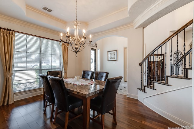 dining space featuring dark wood-type flooring, a raised ceiling, crown molding, and a notable chandelier