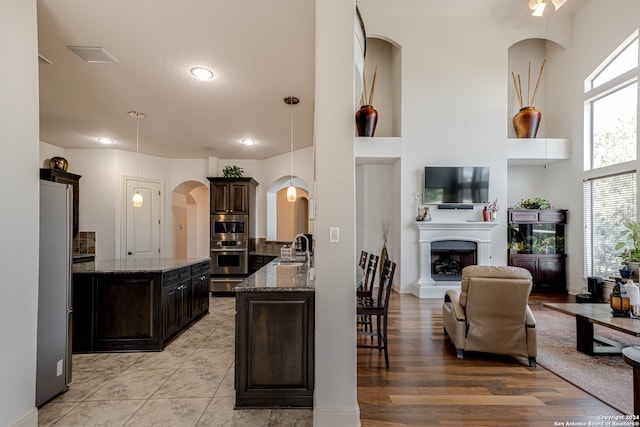 kitchen featuring dark brown cabinets, light hardwood / wood-style floors, sink, and pendant lighting