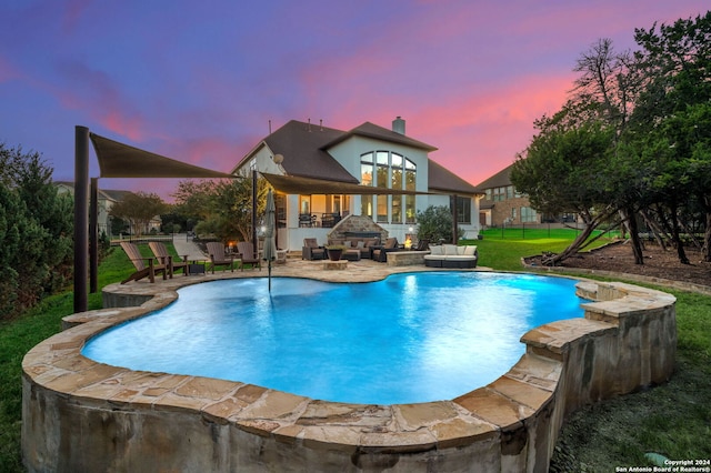 pool at dusk with a patio and a lawn