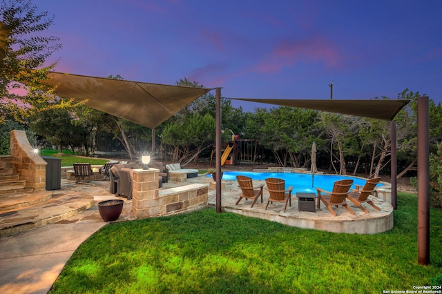 pool at dusk featuring a patio area, a yard, and a playground