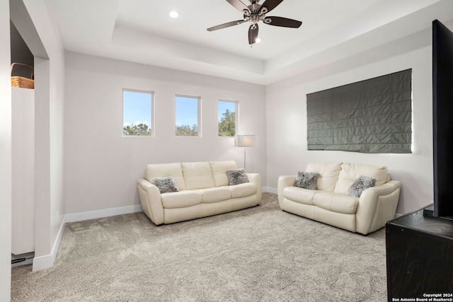 carpeted living room featuring a tray ceiling and ceiling fan