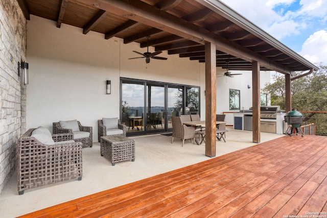 wooden deck with an outdoor kitchen, area for grilling, and ceiling fan