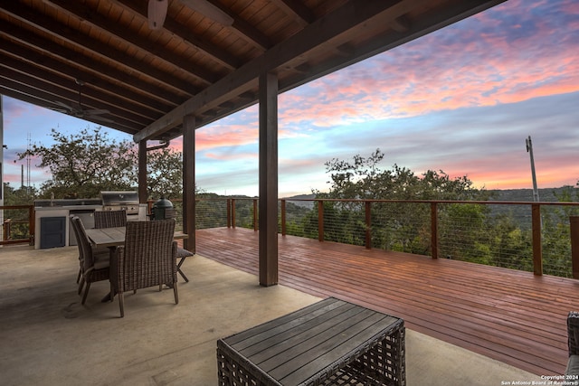 patio terrace at dusk featuring area for grilling and a wooden deck