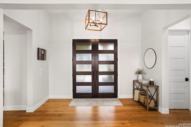 entrance foyer with a chandelier, french doors, and wood-type flooring