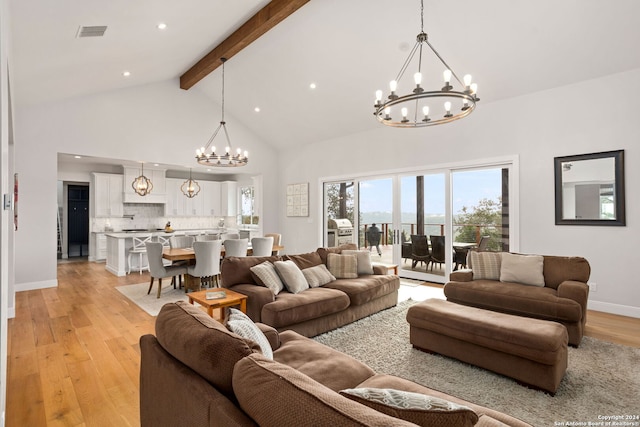 living room with light hardwood / wood-style floors, beamed ceiling, an inviting chandelier, and high vaulted ceiling