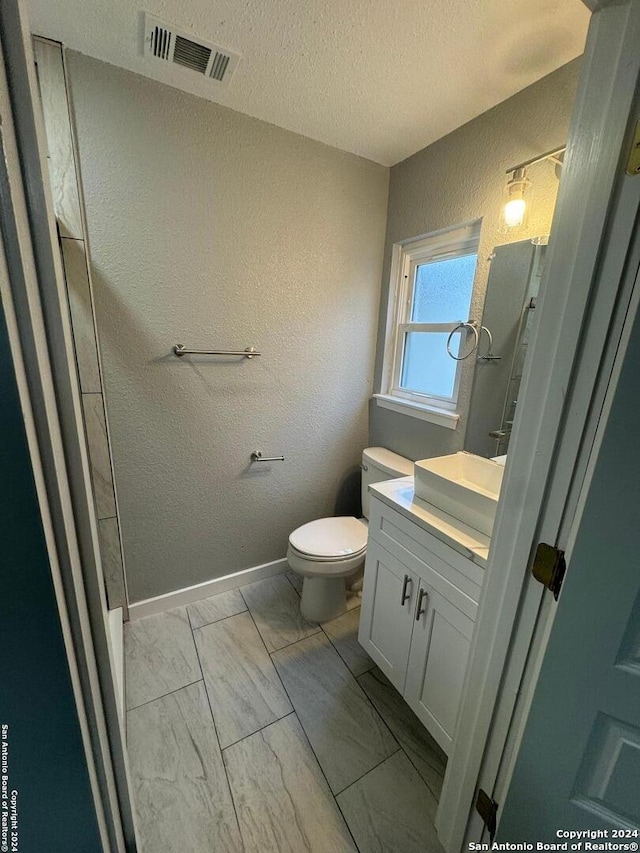 bathroom with toilet, vanity, and a textured ceiling