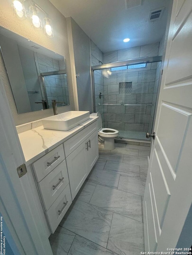 bathroom featuring vanity, toilet, and a shower with door