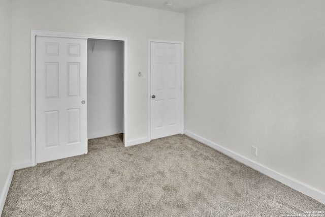 unfurnished bedroom featuring light carpet and a closet