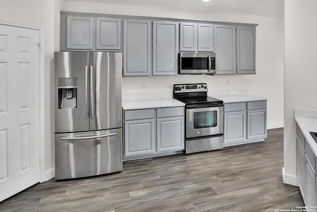 kitchen with stainless steel appliances, hardwood / wood-style flooring, and gray cabinetry