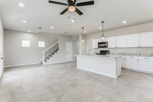 kitchen featuring white cabinets, a center island with sink, sink, and black appliances