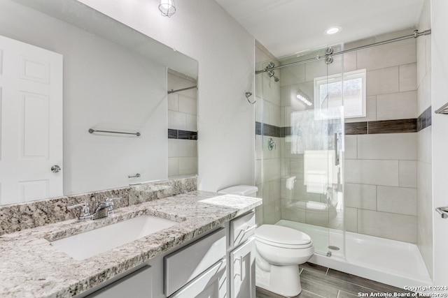 bathroom with walk in shower, vanity, and toilet