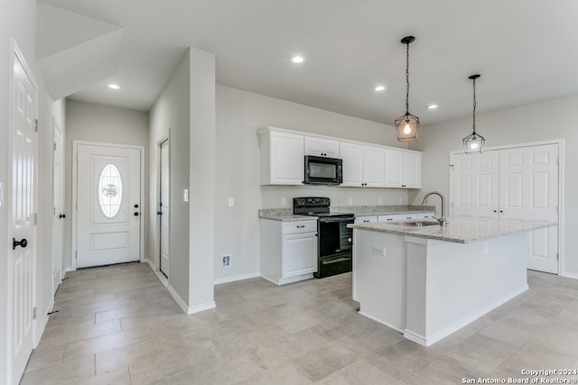 kitchen with white cabinetry, sink, black appliances, light stone counters, and a kitchen island with sink