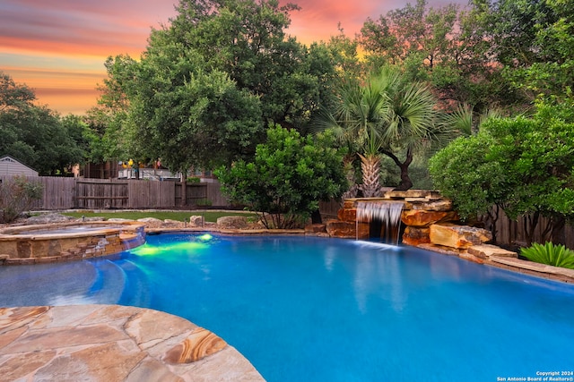 pool at dusk with an in ground hot tub