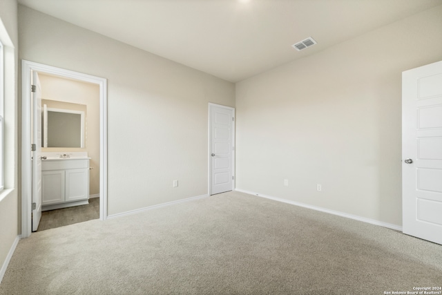 unfurnished bedroom with light colored carpet and connected bathroom