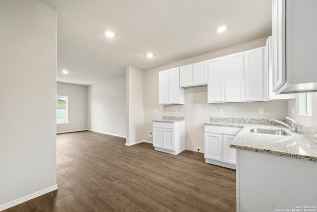 kitchen with dark hardwood / wood-style flooring, white cabinetry, sink, and light stone counters