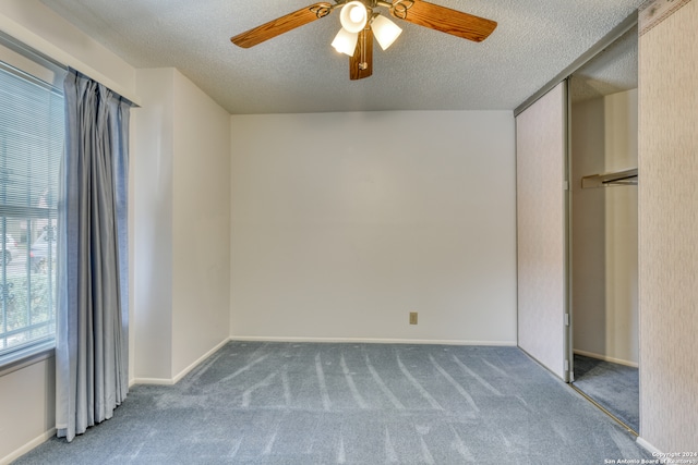 unfurnished bedroom with a closet, carpet, a textured ceiling, and ceiling fan