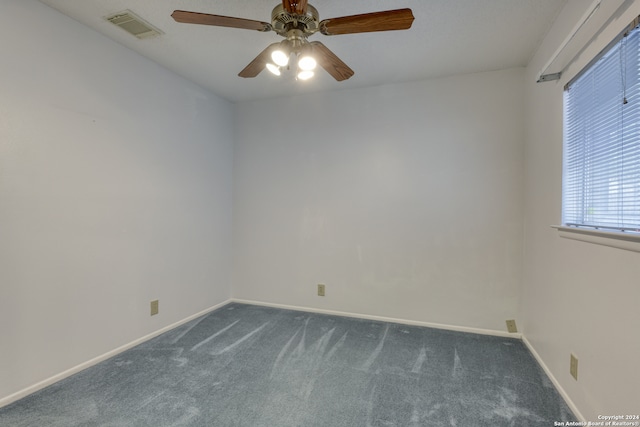 spare room with ceiling fan and dark carpet