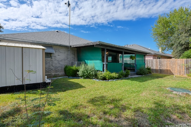 rear view of house featuring a shed and a yard