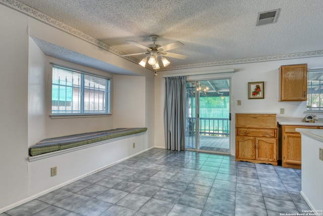 interior space featuring a textured ceiling, a wealth of natural light, ceiling fan, and light tile patterned floors