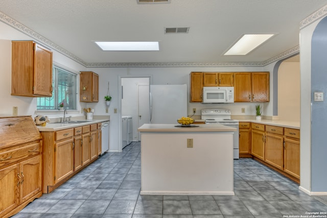 kitchen with a center island, a textured ceiling, sink, white appliances, and washer and dryer