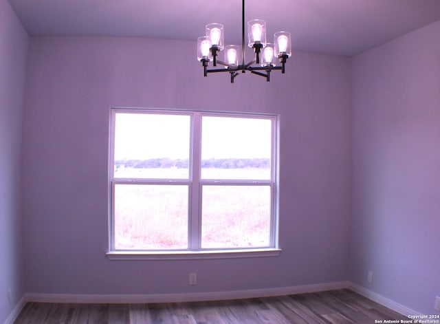 unfurnished room featuring a notable chandelier and wood-type flooring