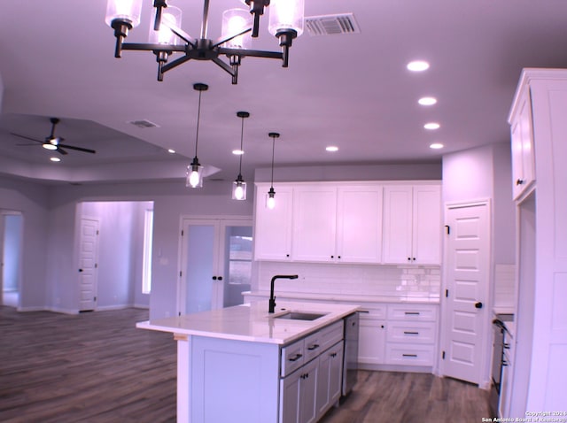 kitchen featuring white cabinets, decorative light fixtures, sink, and a kitchen island with sink