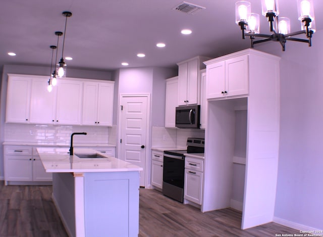 kitchen featuring a kitchen island with sink, hanging light fixtures, dark hardwood / wood-style floors, appliances with stainless steel finishes, and white cabinetry