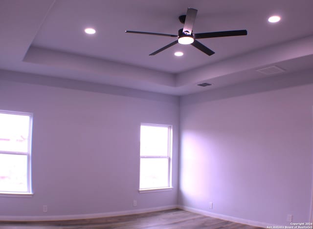 empty room featuring hardwood / wood-style floors, a raised ceiling, and ceiling fan