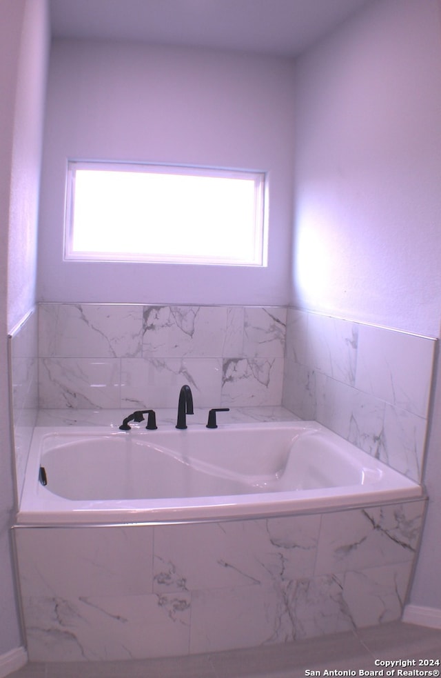 bathroom featuring plenty of natural light and tiled tub