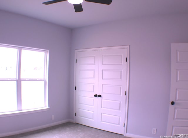 unfurnished bedroom featuring ceiling fan, a closet, and light carpet