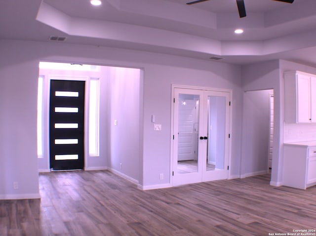 foyer entrance featuring a raised ceiling, french doors, and light hardwood / wood-style flooring