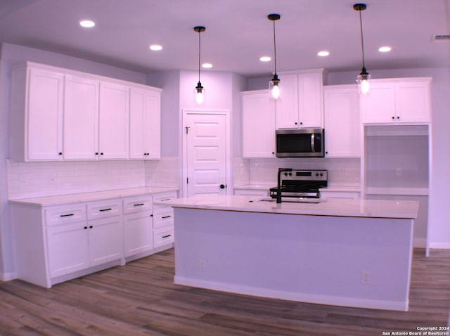 kitchen featuring white cabinetry, wood-type flooring, decorative light fixtures, a center island with sink, and appliances with stainless steel finishes