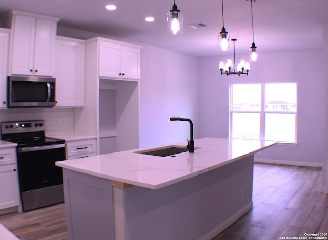 kitchen with white cabinetry, hanging light fixtures, stainless steel appliances, and sink